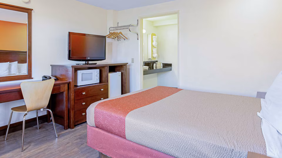 Queen room with microwave, refrigerator, television, and desk